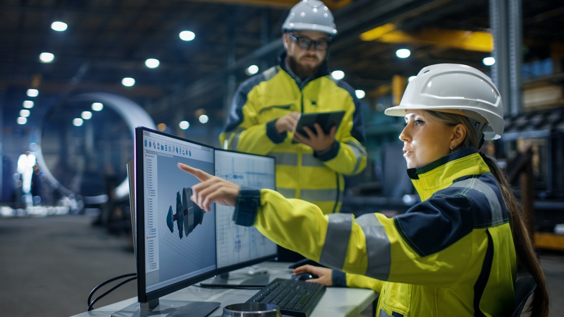 Worker in front of computer screens in an industrial environment